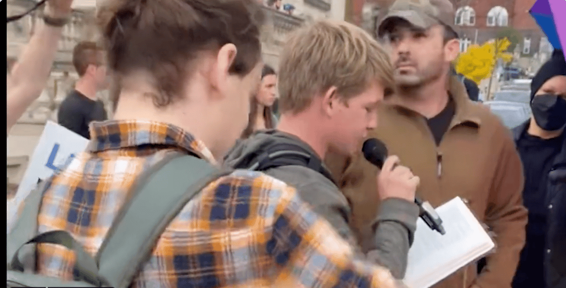 (WATCH) College student reading Bible over microphone mocked, Bible torn apart and pages eaten by angry spectators